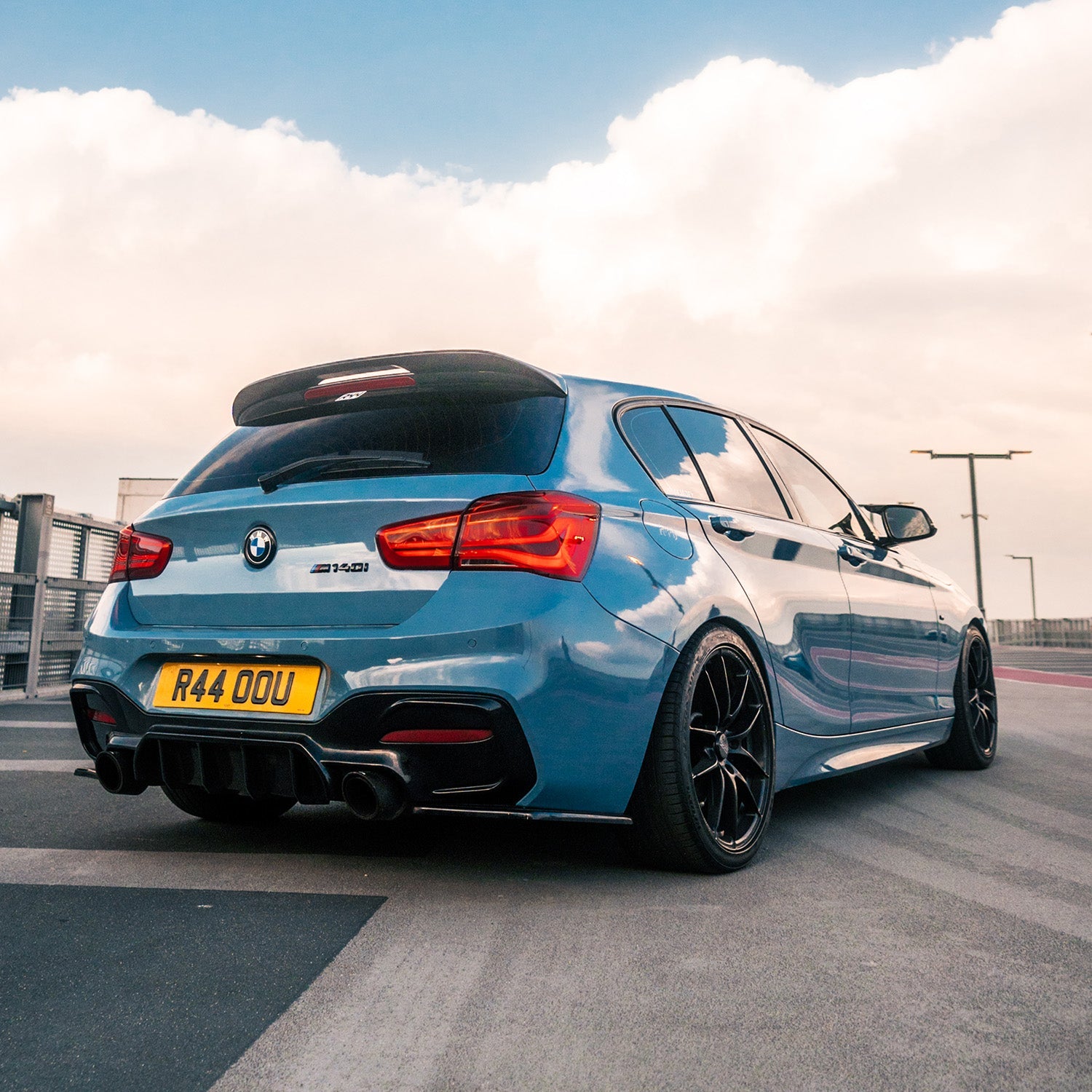 Blue BMW car on a road with a cloudy sky